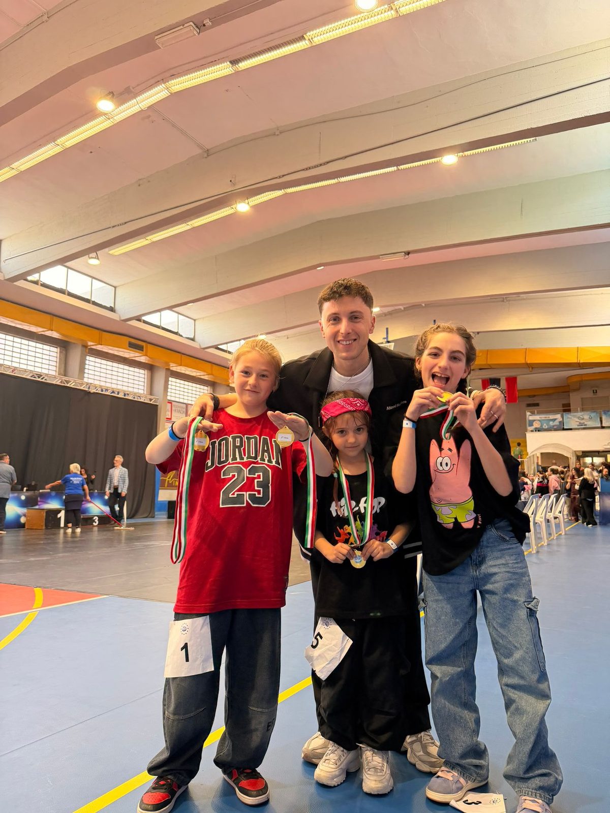 Bambini della scuola con le medaglie insieme al loro coach di hip hop